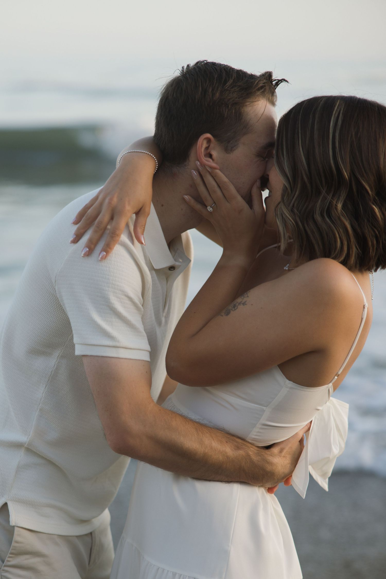 Couple kissing in front of the waves during an engagement session at El Matador Beach in Malibu