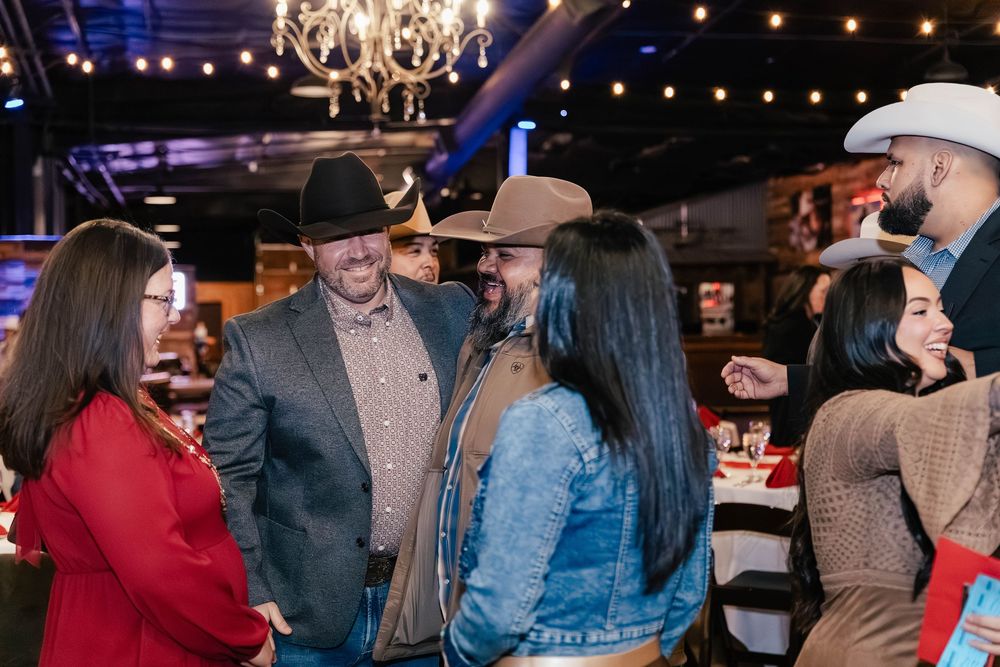Group of guests in western attire socializing under a chandelier at a themed event.