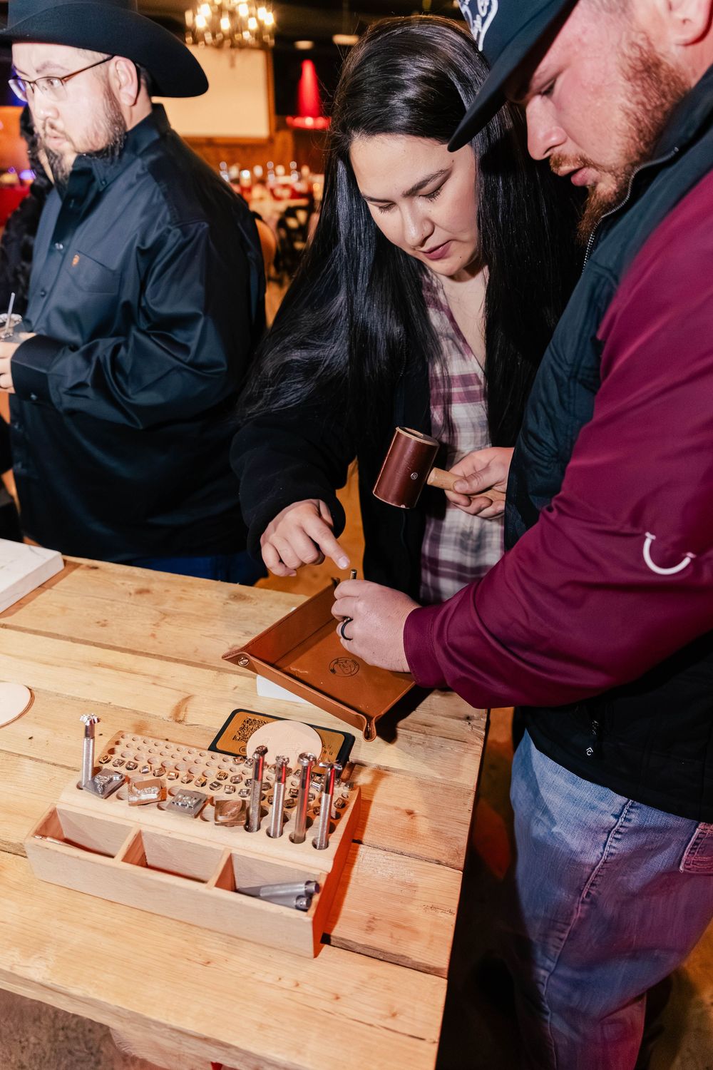 Guests examining items at a wooden display table during a western-themed event.