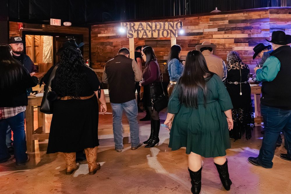 Guests mingle and socialize at a dimly lit event venue with decorative lighting.