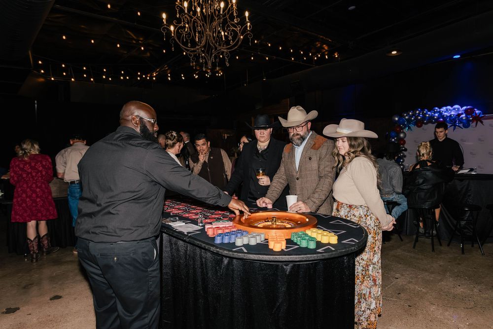 Event space with elegant chandeliers and guests seated at tables in dark ambient lighting.