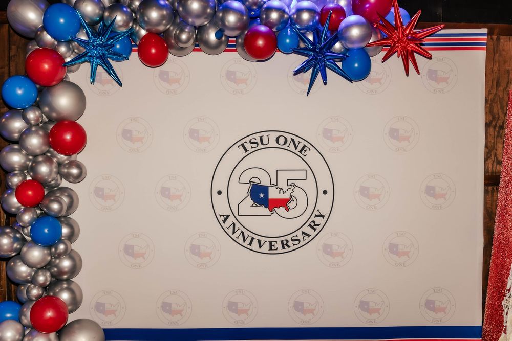 Red, white and blue balloon decorations with star accents against a light colored wall.