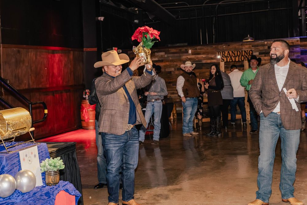 Wide view of an indoor event space with guests in western attire and stage lighting.