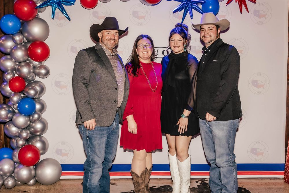 Group photo against a festive red, white and blue balloon arch backdrop at an event.