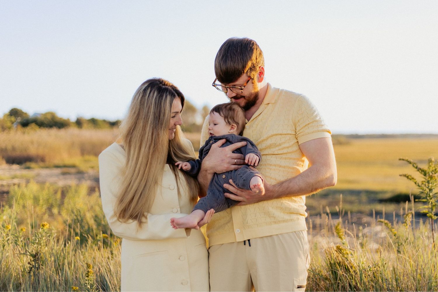 A romantic engagement photo session in a golden marsh field during sunset.