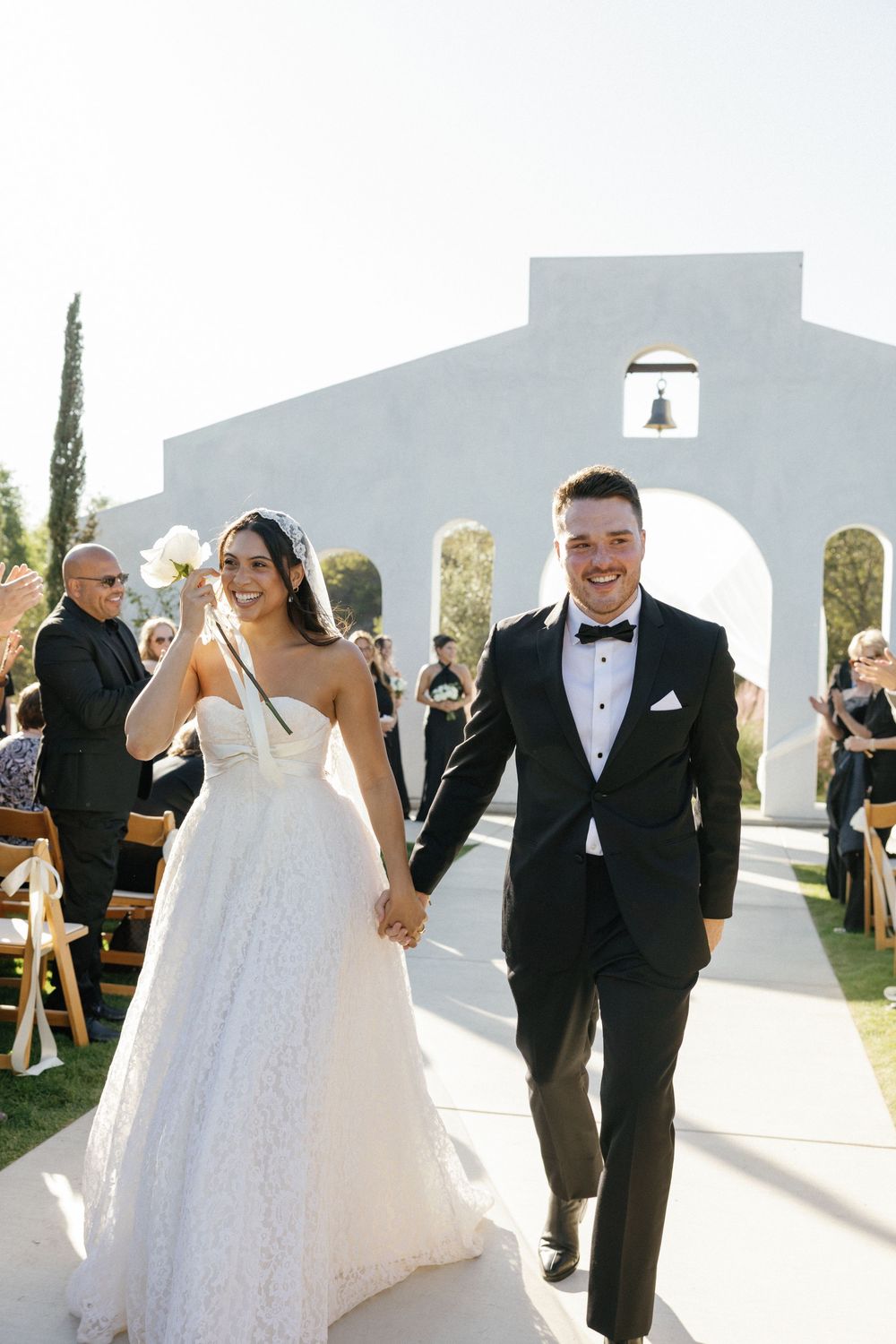 Wedding ceremony setup with modern white architectural elements and guests seated outdoors.
