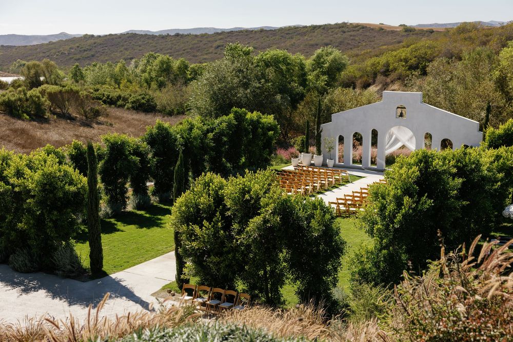 Panoramic view of a hillside estate with white buildings nestled among trees and landscaped grounds.
