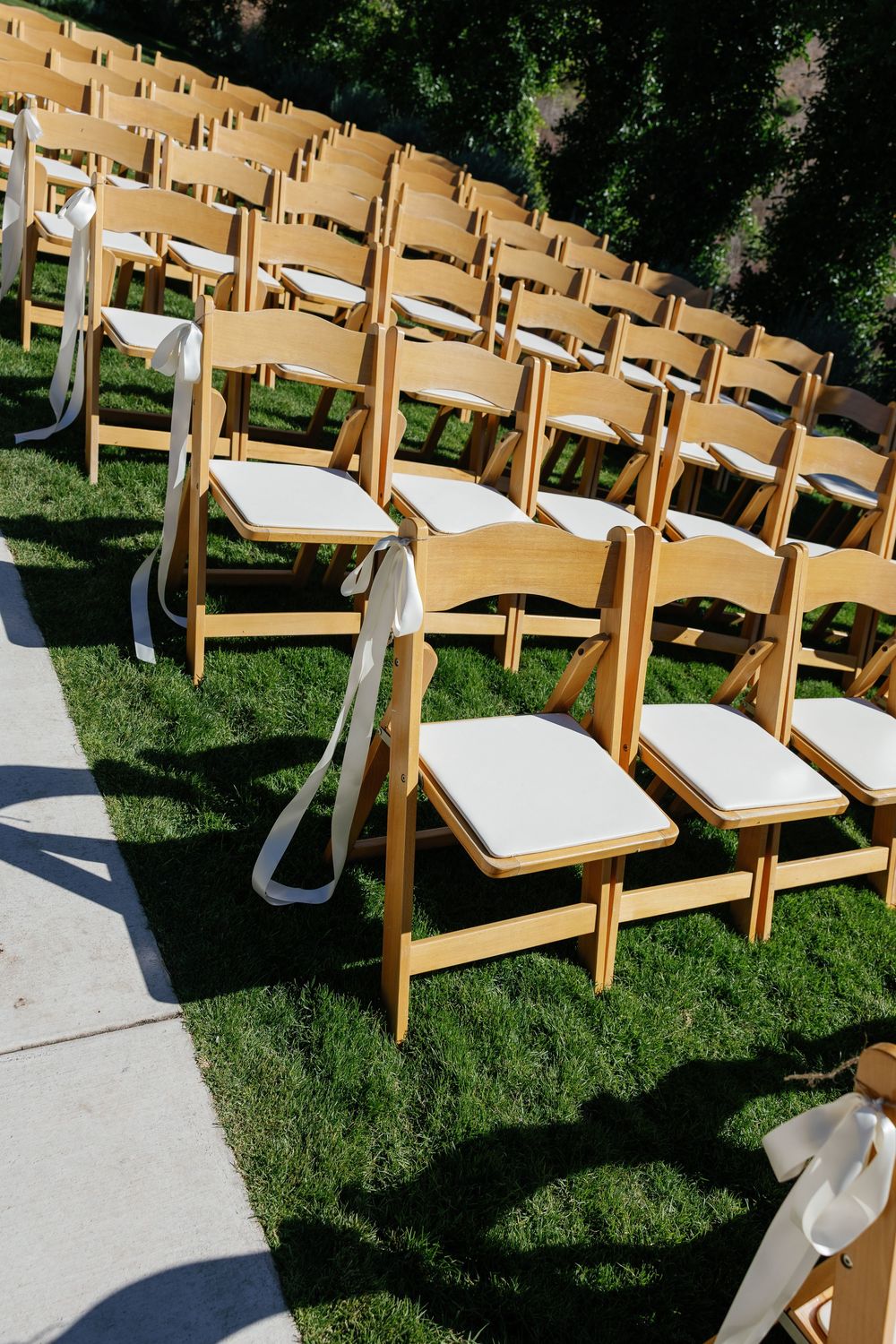 Rows of wooden folding chairs set up on grass for an outdoor wedding ceremony.