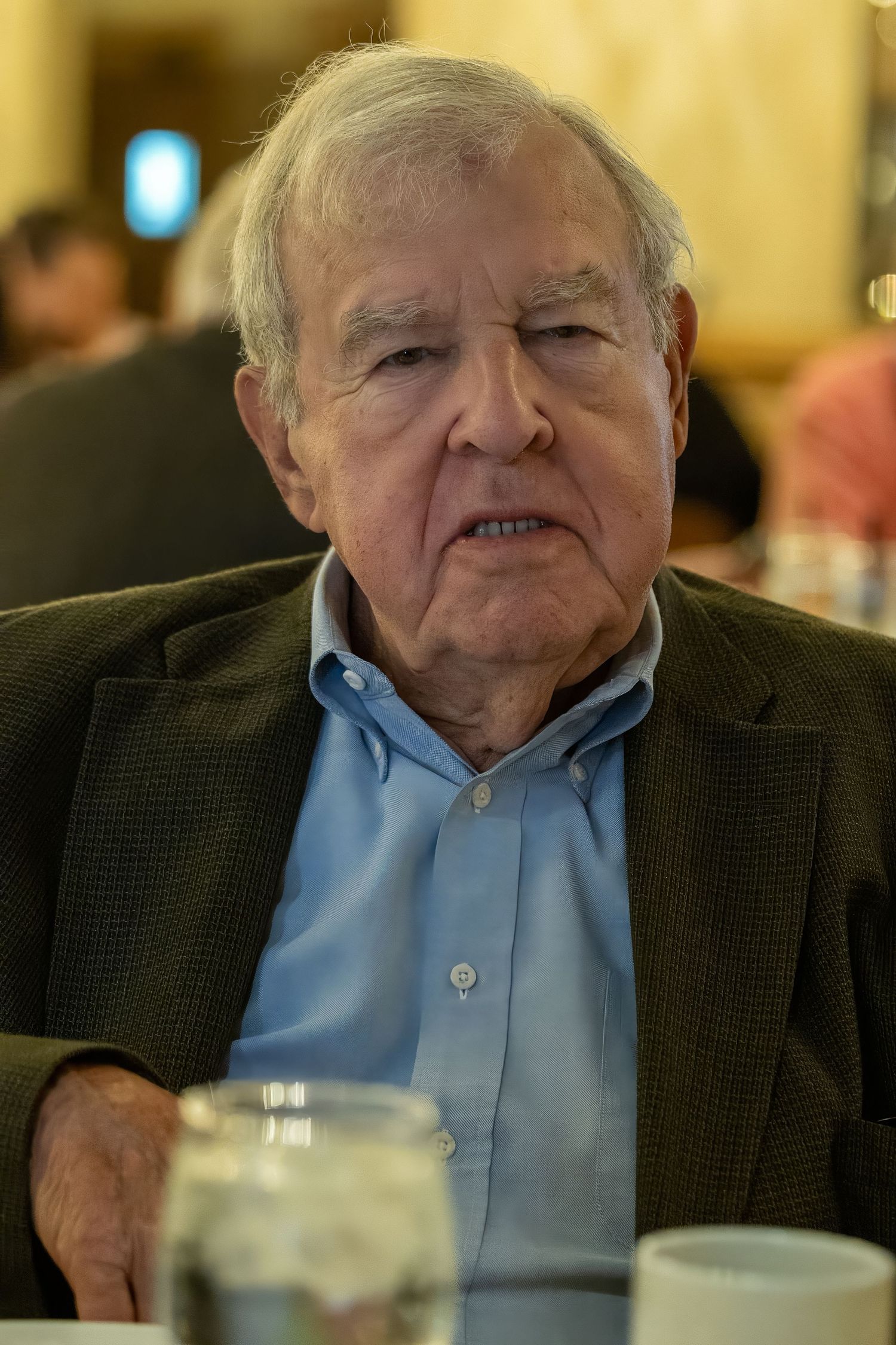 Frederick Maryland Wedding Photographer   An elderly person in a dark blazer and blue shirt sits at a dining table.