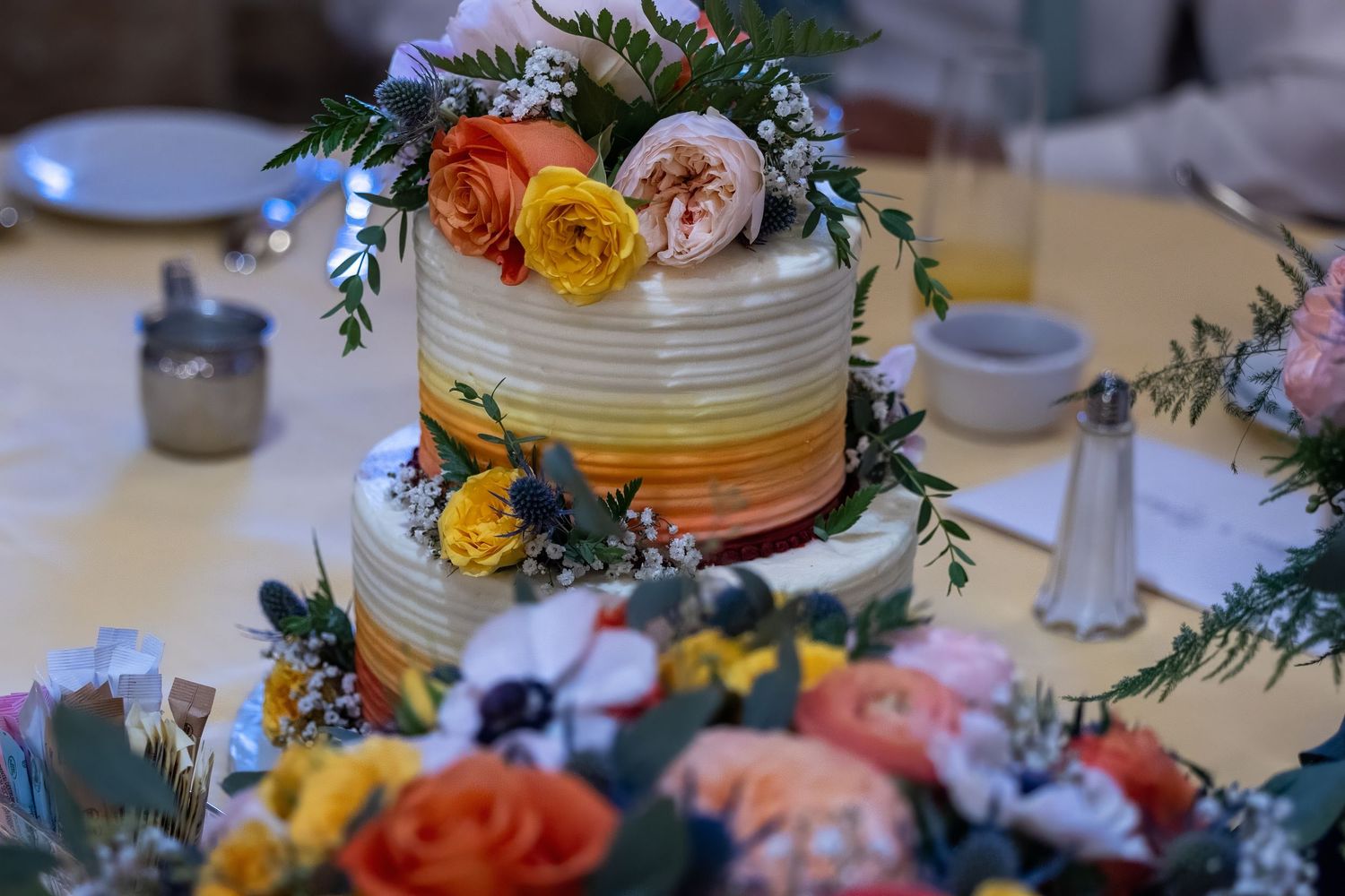 Frederick Maryland Wedding Photographer   A wedding cake decorated with fresh orange and yellow flowers and greenery.