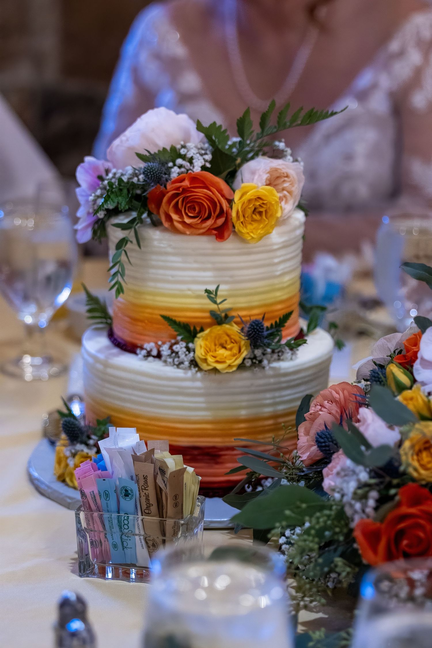 Frederick Maryland Wedding Photographer   A tiered wedding cake decorated with orange and yellow roses and greenery on a white tablecloth.