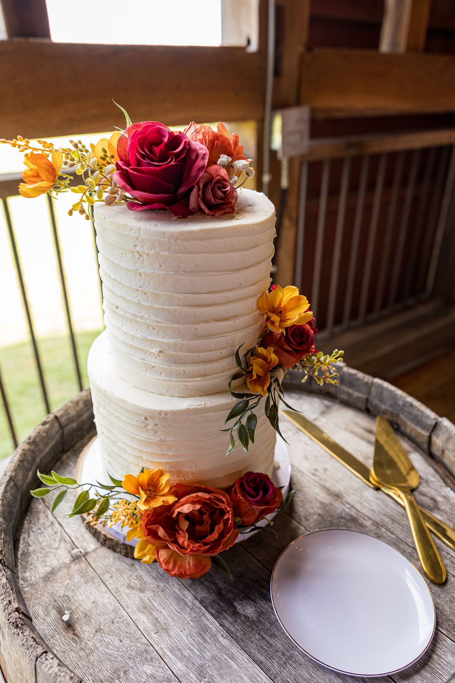 frederick maryland wedding photographer White wedding cakes adorned with autumn-colored flowers displayed on rustic wooden stands.