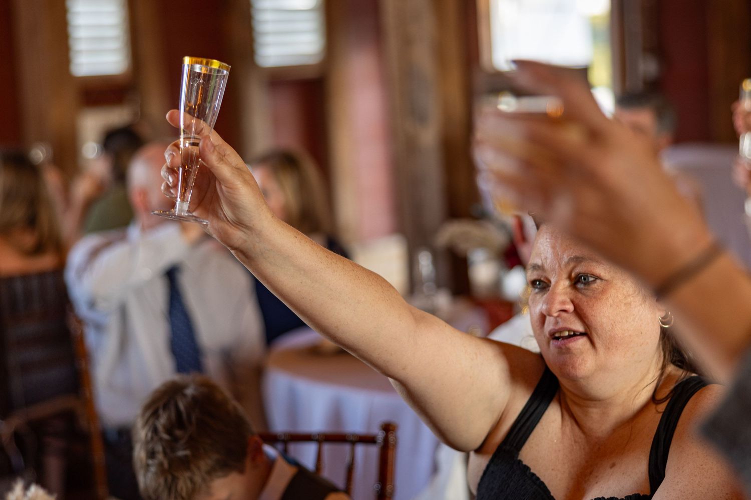 frederick maryland wedding photographer Wedding reception guests holding up champagne flutes during a toast moment.