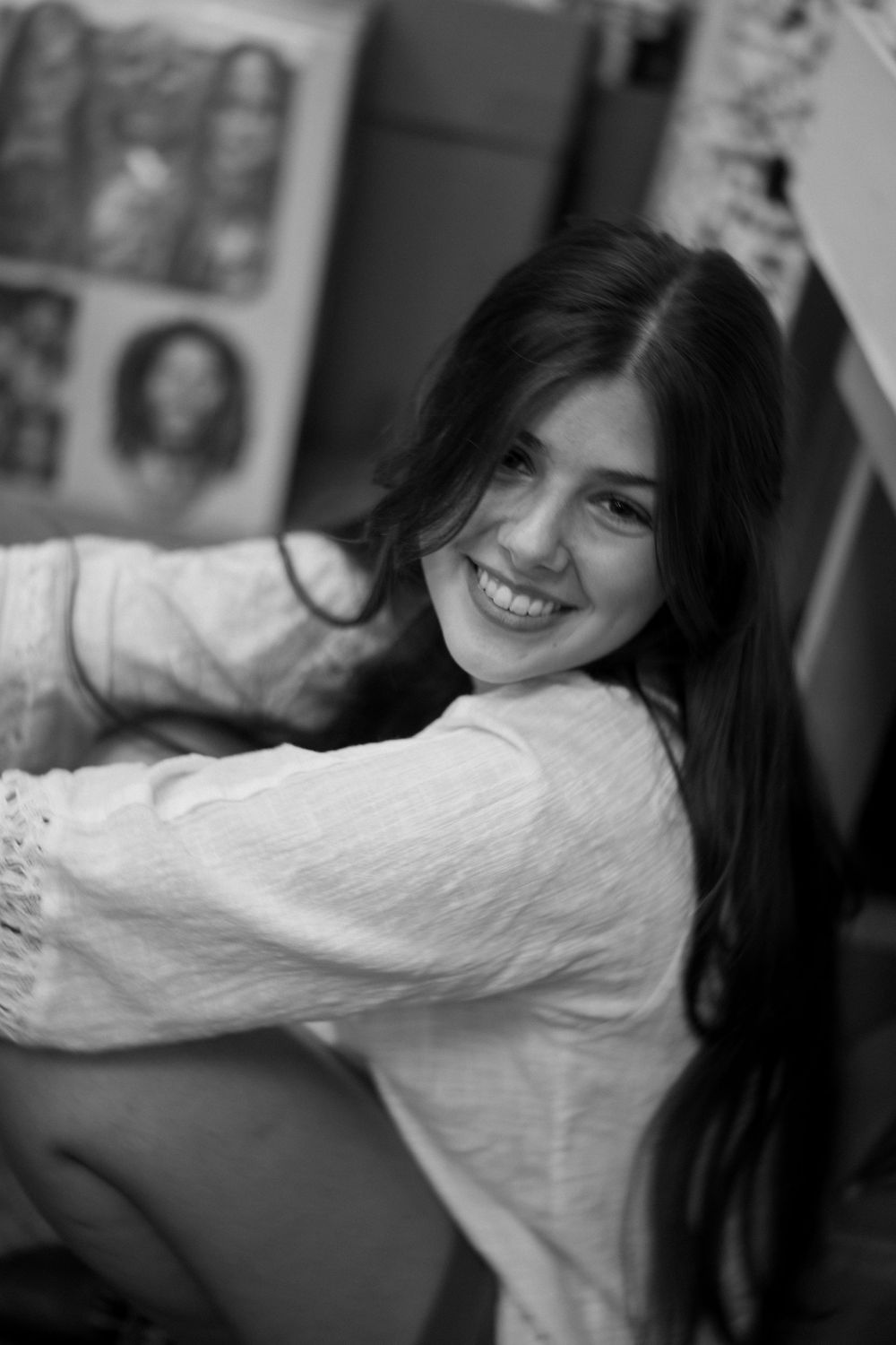 Black and white portrait of a smiling young woman with long dark hair wearing a white sweater.
