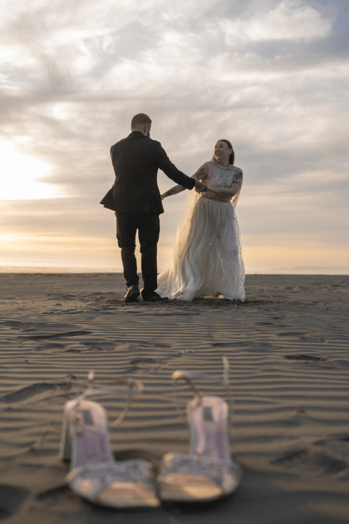 A young couple kicks off their shoes and dances on a Washington coast beach after eloping with their two dogs in Olympic National Park.