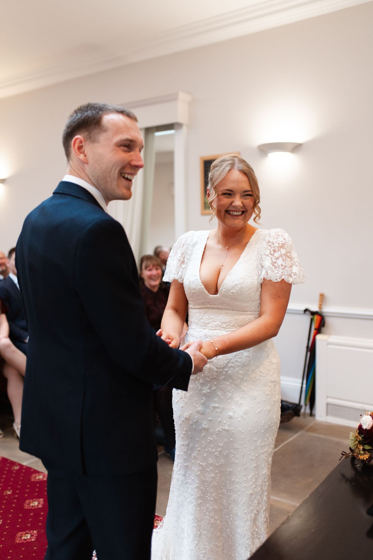 A happy couple shares a joyful moment during their first dance at a wedding reception in a bright indoor venue.