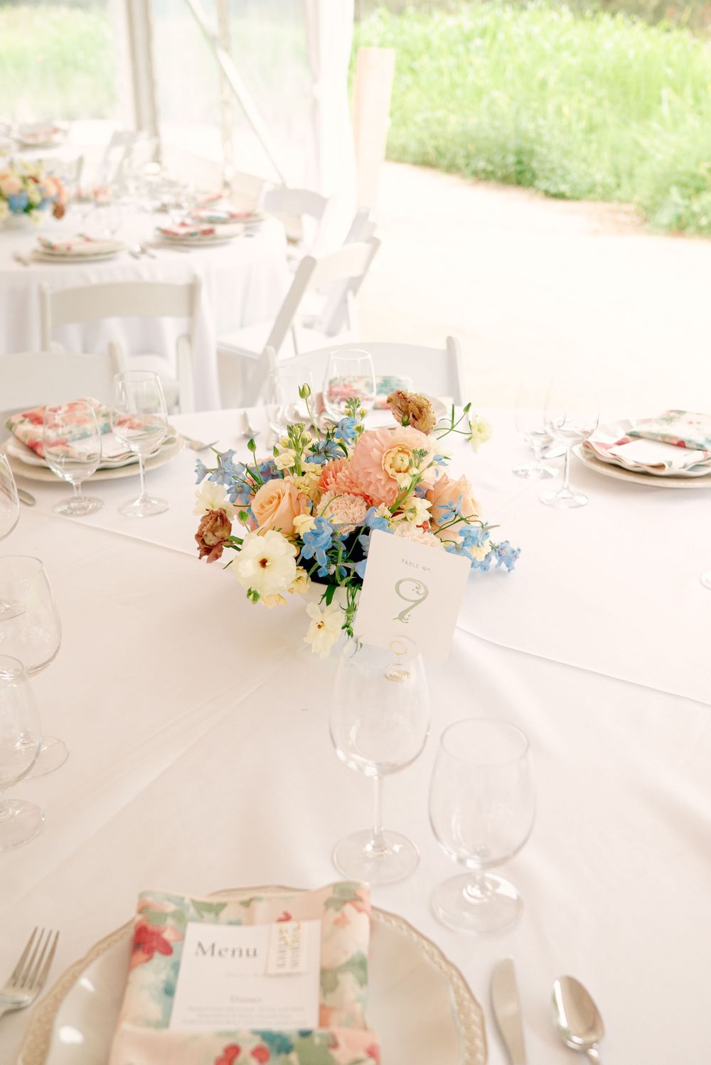 Elegant wedding table setting with soft pastel floral centerpieces, white linens, and crystal glassware.