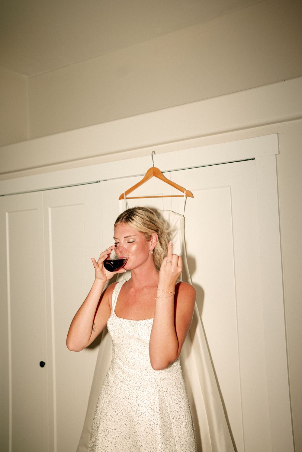A sequence of photos showing someone in white taking sips of red wine against a plain wall background.