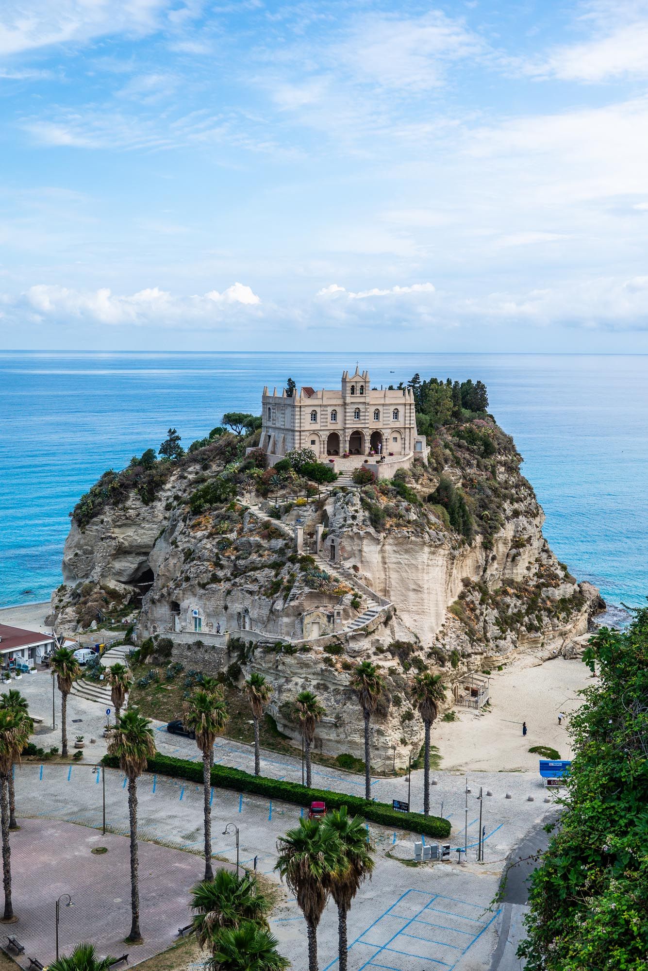 Scenic coastal view of Tropea, Italy with white buildings perched on dramatic limestone cliffs overlooking turquoise waters.