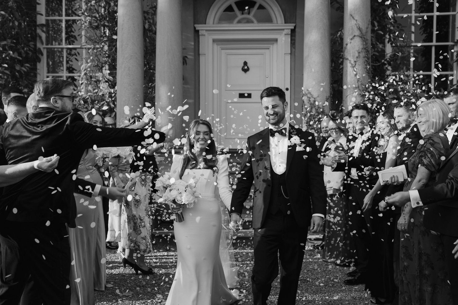 wedding guests throwing confetti over the bride and groom at Iscoyd park