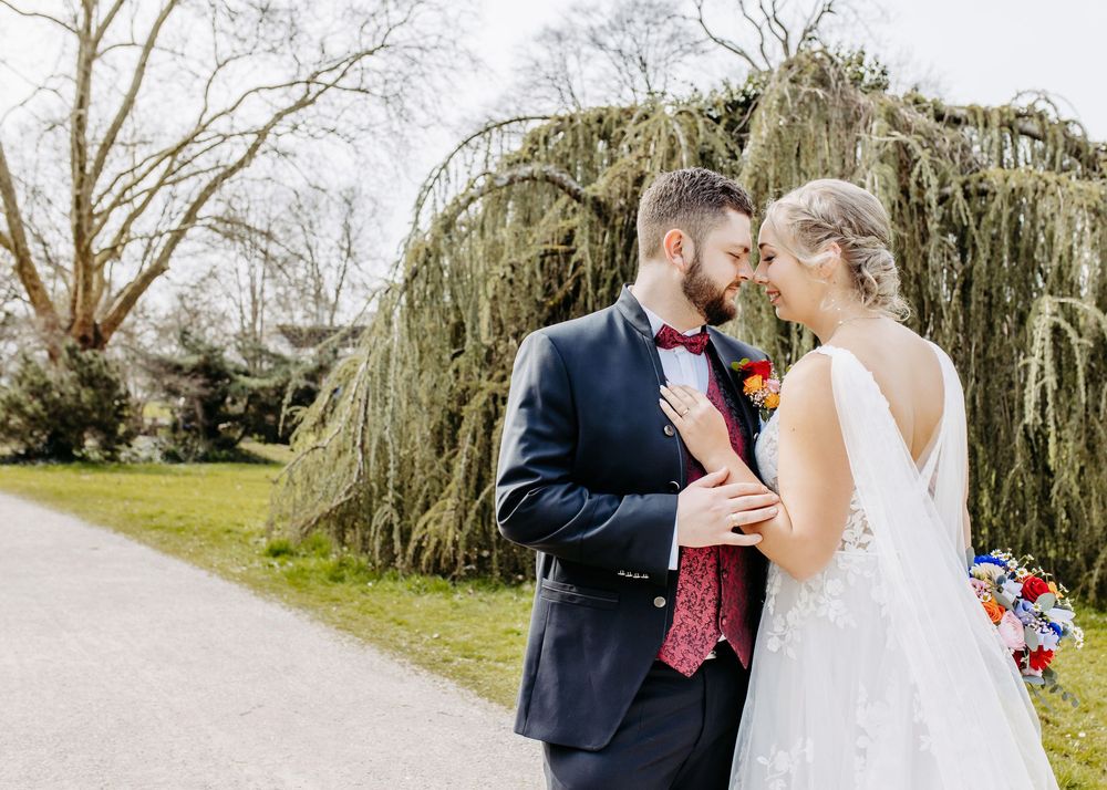A couple shares a romantic moment together on a tree-lined path during their wedding day celebration.