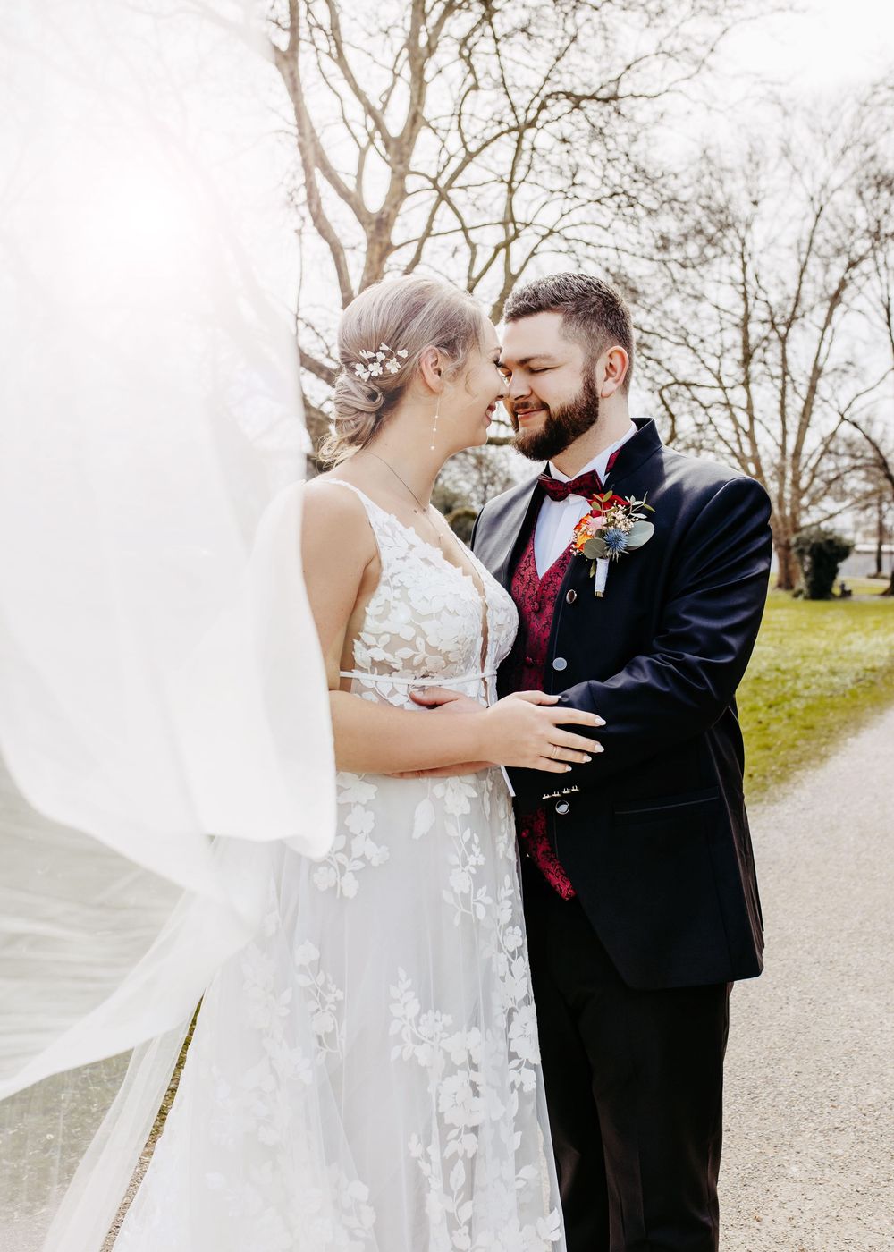 A romantic wedding couple shares intimate moments in a series of outdoor portraits along a tree-lined path.