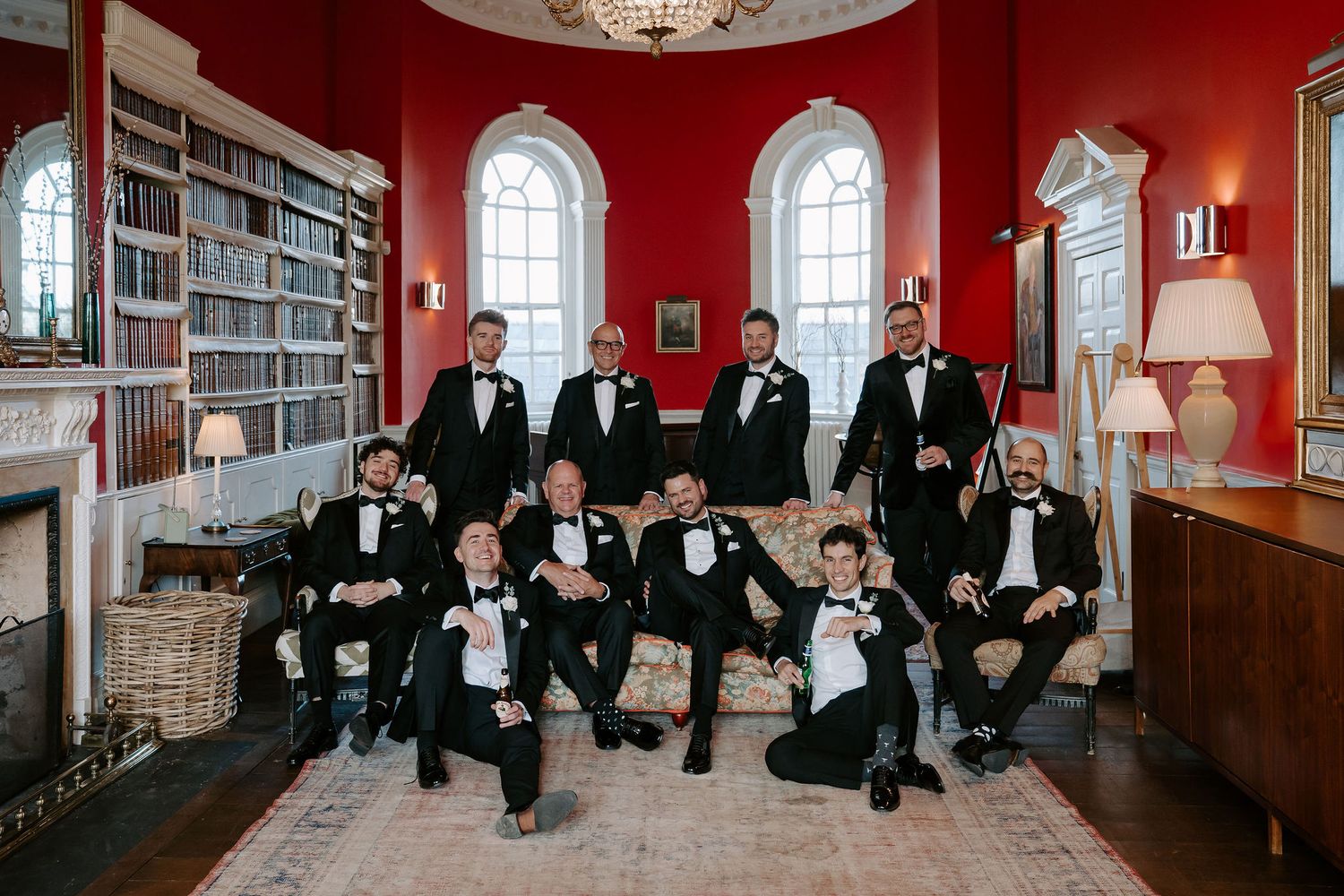 groom and groomsmen sitting on couch drinking whiskey in the library at Iscoyd park