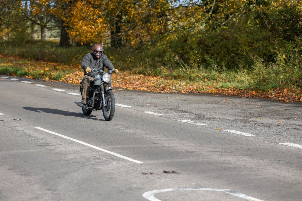 Motorcyclist navigating a scenic country road surrounded by fall foliage and golden trees.