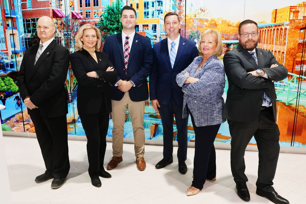 A group of six business professionals stand together against a colorful urban mural background.