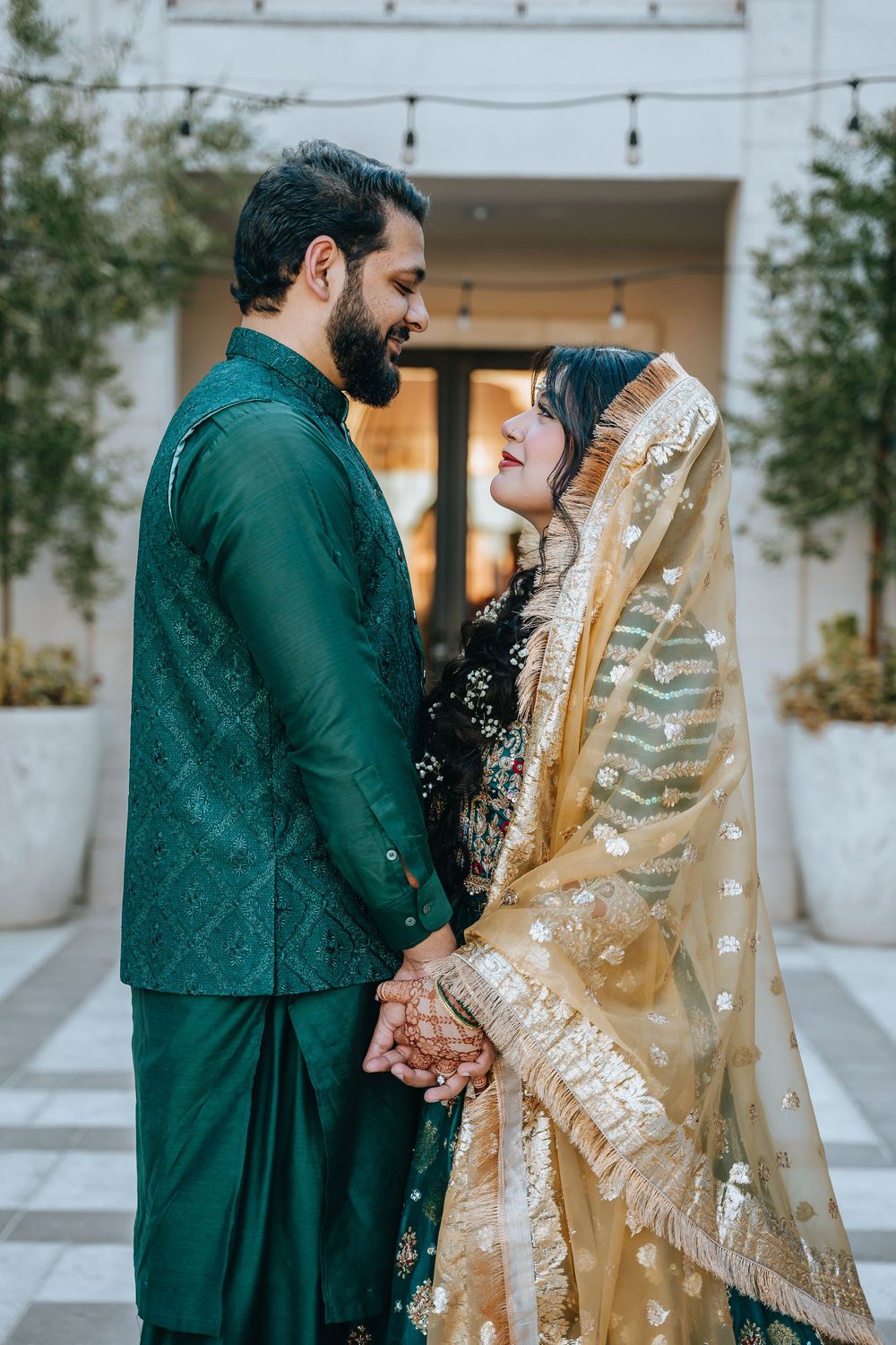 A couple in traditional South Asian attire sharing a romantic moment under a covered walkway.