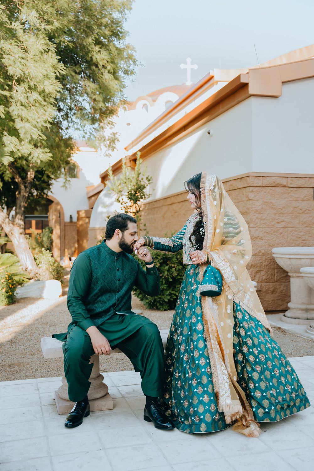 A couple in matching green outfits poses together near a church exterior.