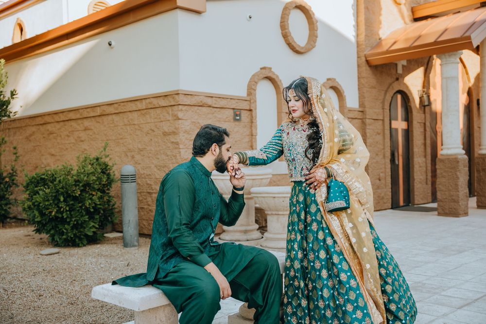 Couple in coordinated green and turquoise outfits photographed in an elegant colonnade setting.