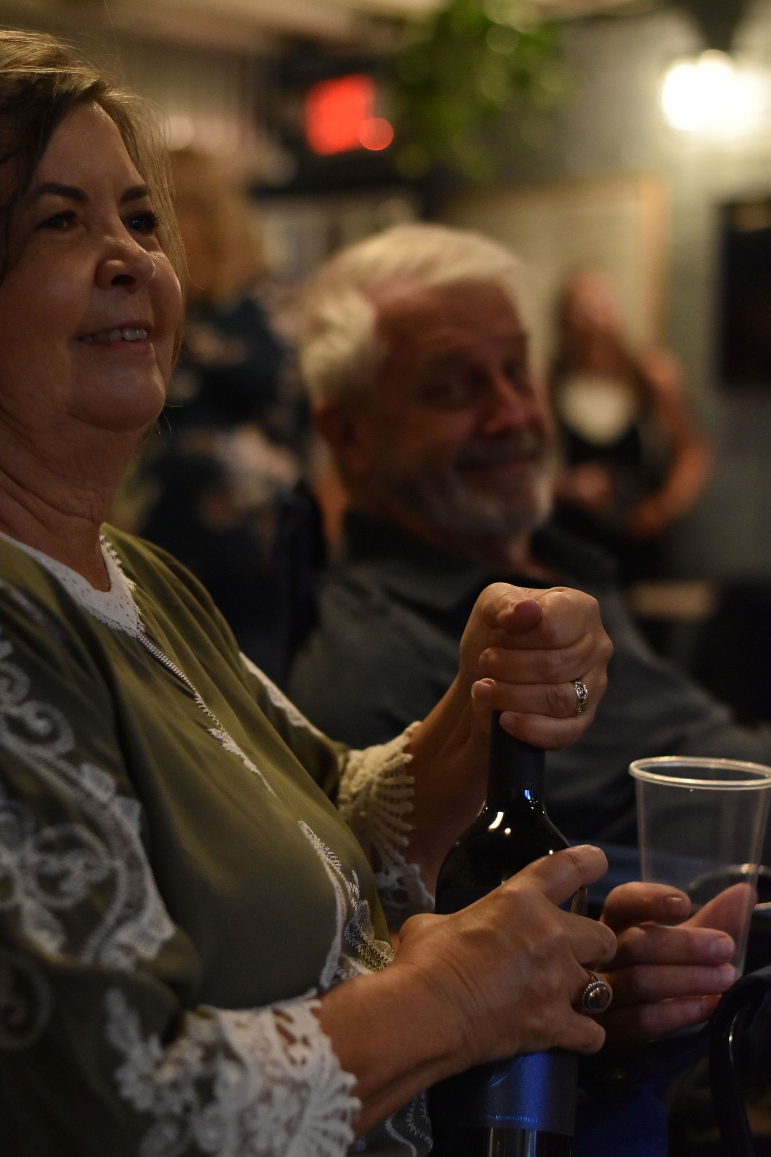 Two people enjoying drinks and conversation in a dimly lit social setting.