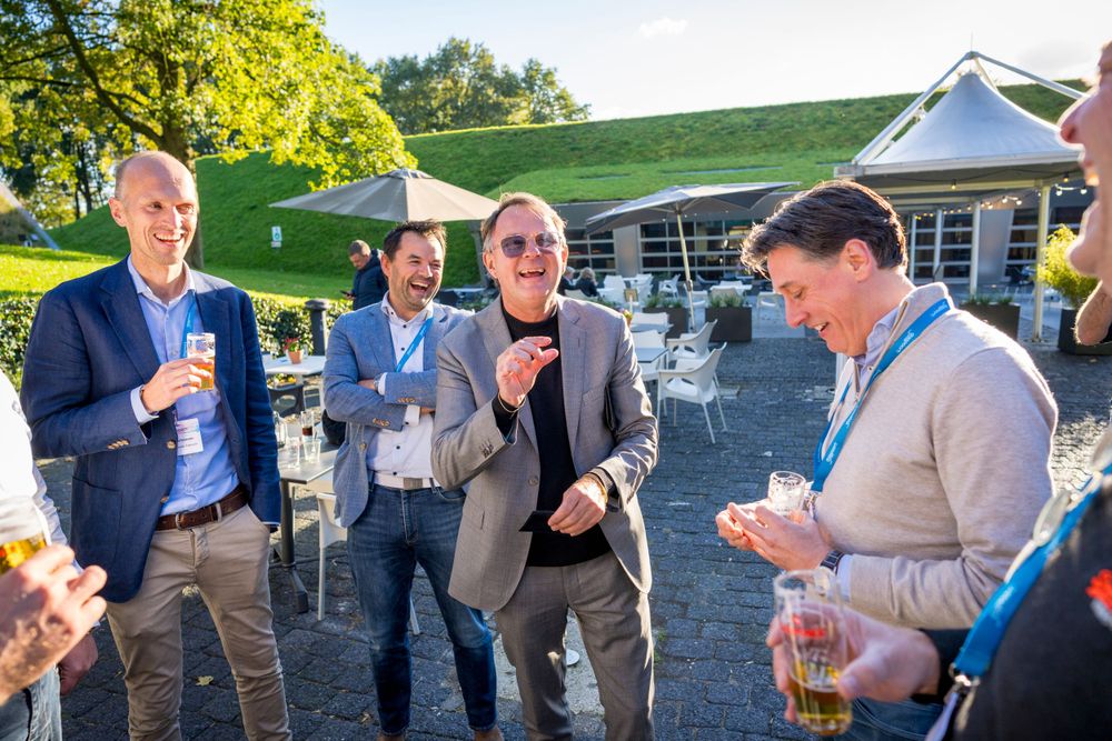 Business professionals enjoying drinks and conversation during an outdoor networking event.