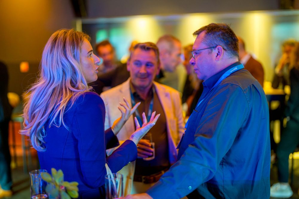 Group engaged in lively conversation at evening networking event with ambient lighting.