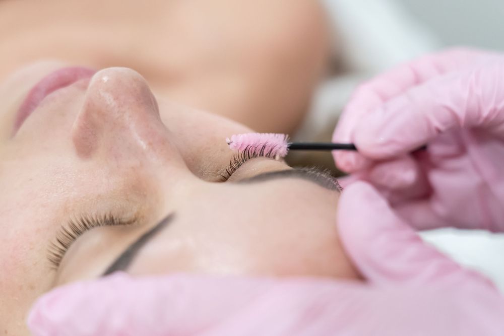 Close-up of eyelash treatment being performed with precision tweezers.
