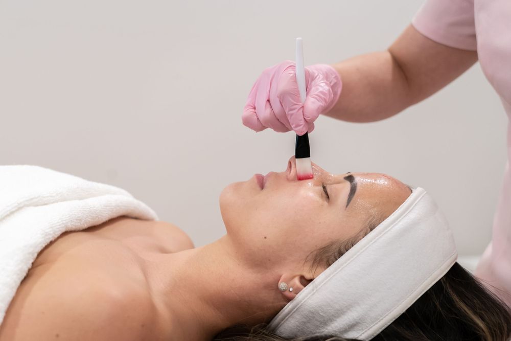 Skincare specialist applying facial treatment with precise brush technique.