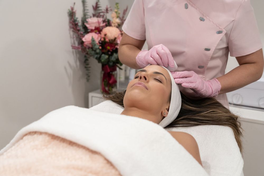 Client receiving relaxing facial treatment on spa bed with white headband.