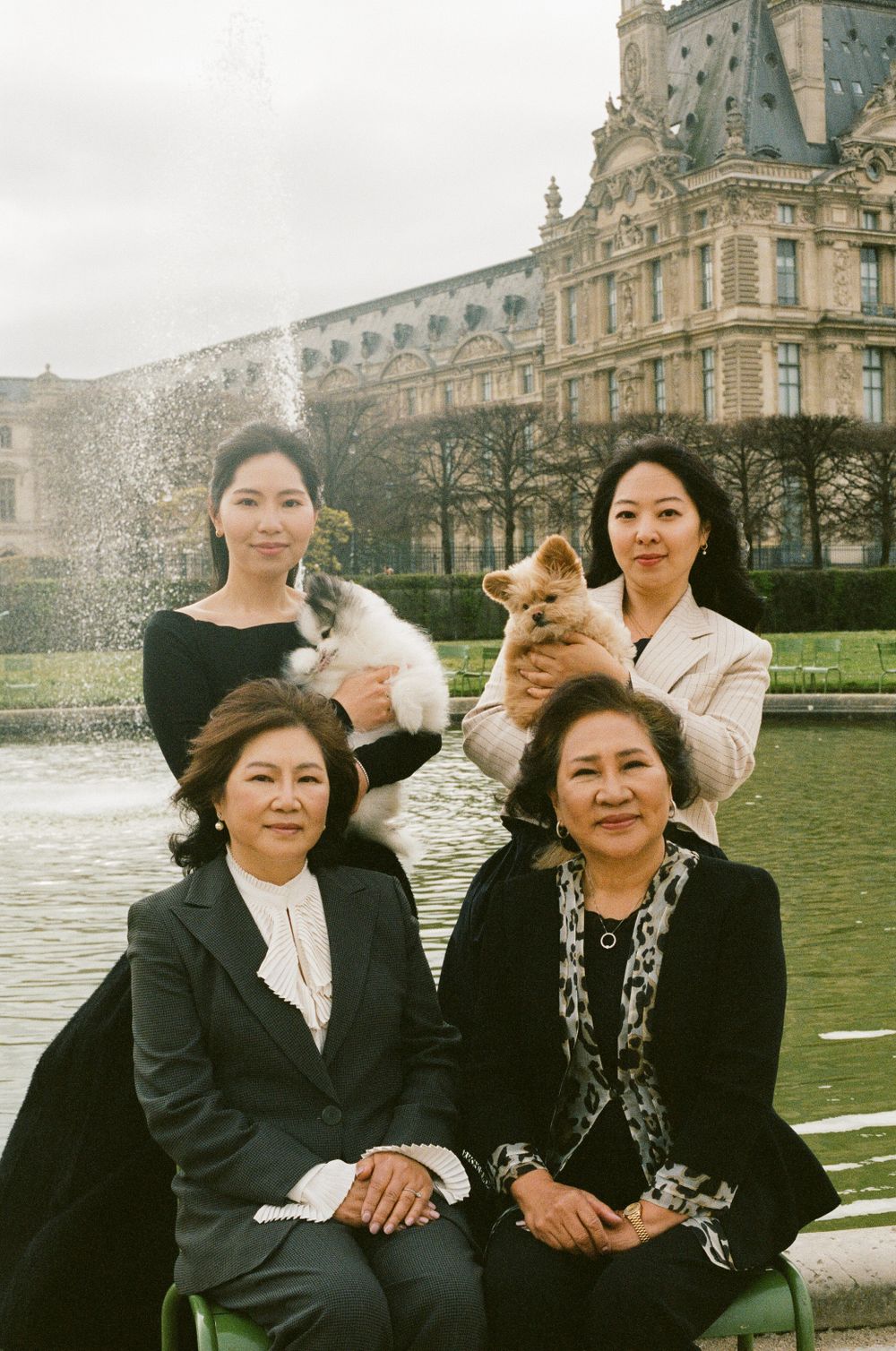 A multi-generational family poses with their pets in front of the grand Louvre Museum in Paris.