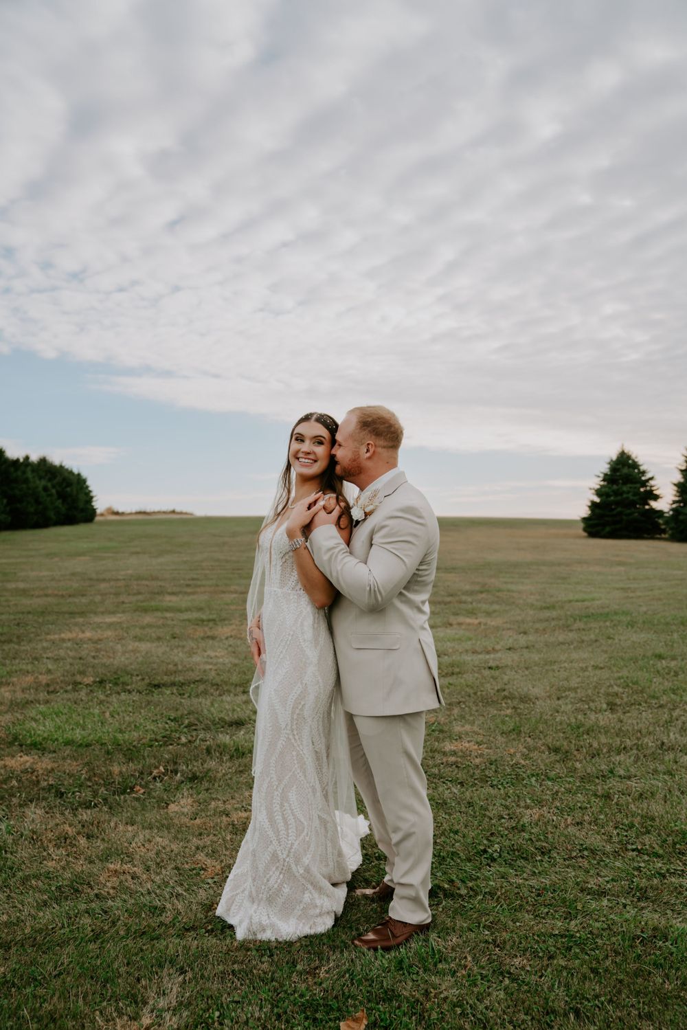 A romantic moment under dramatic clouds in an open field.