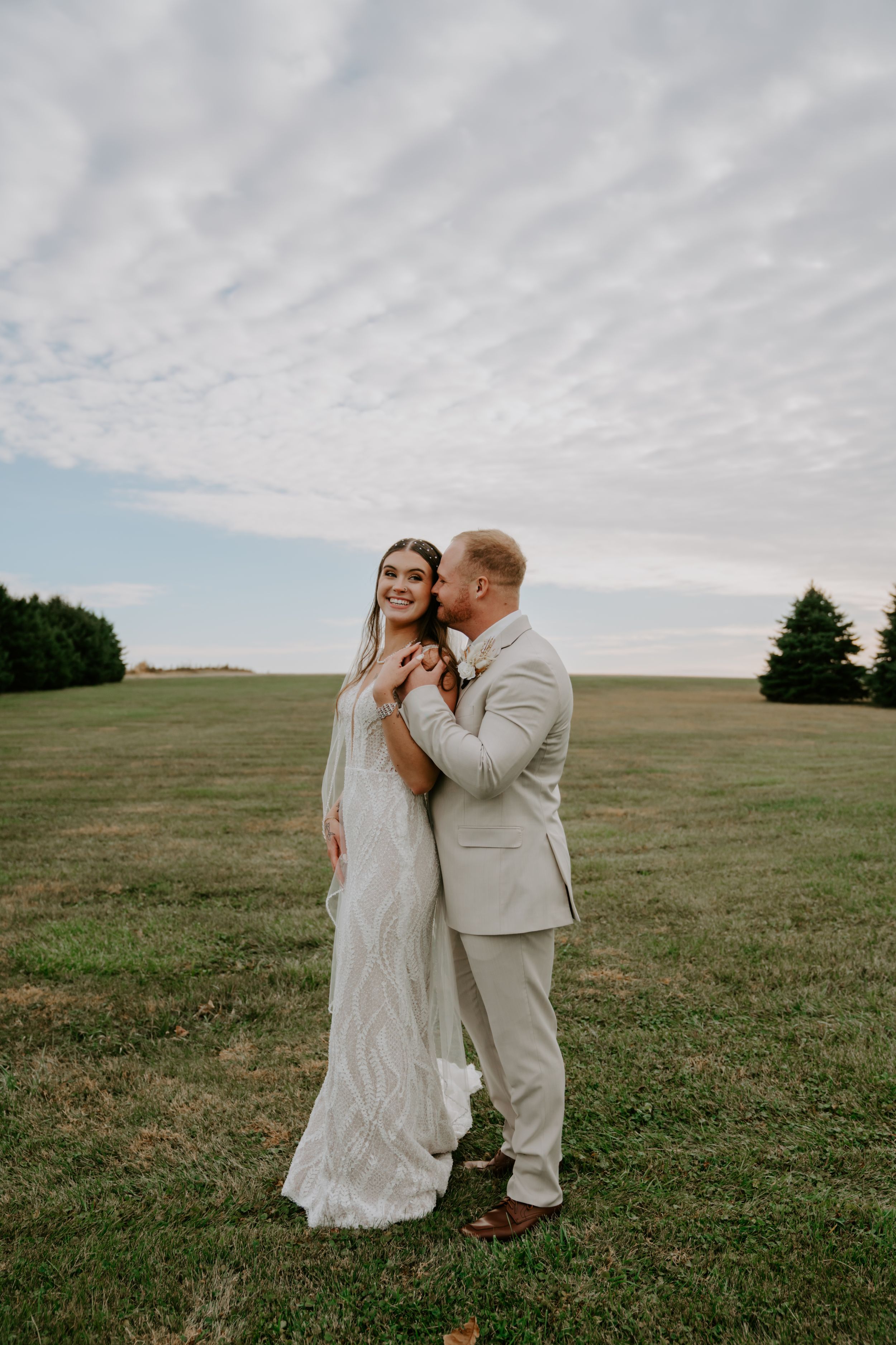 A romantic moment under dramatic clouds in an open field.
