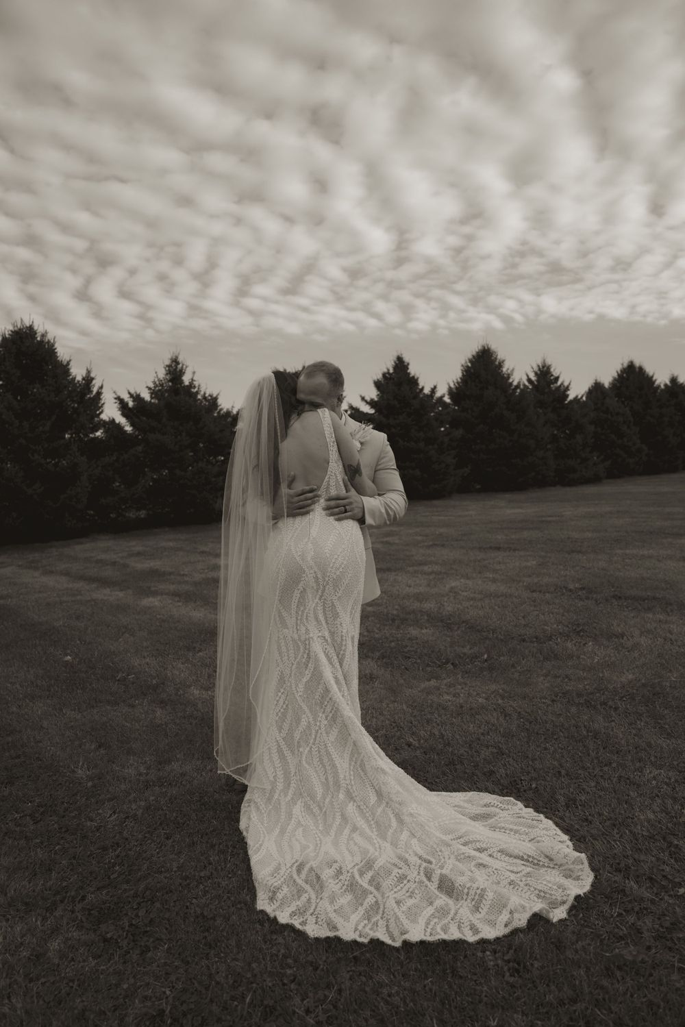 A flowing white wedding dress creates an ethereal silhouette against a cloudy sky.