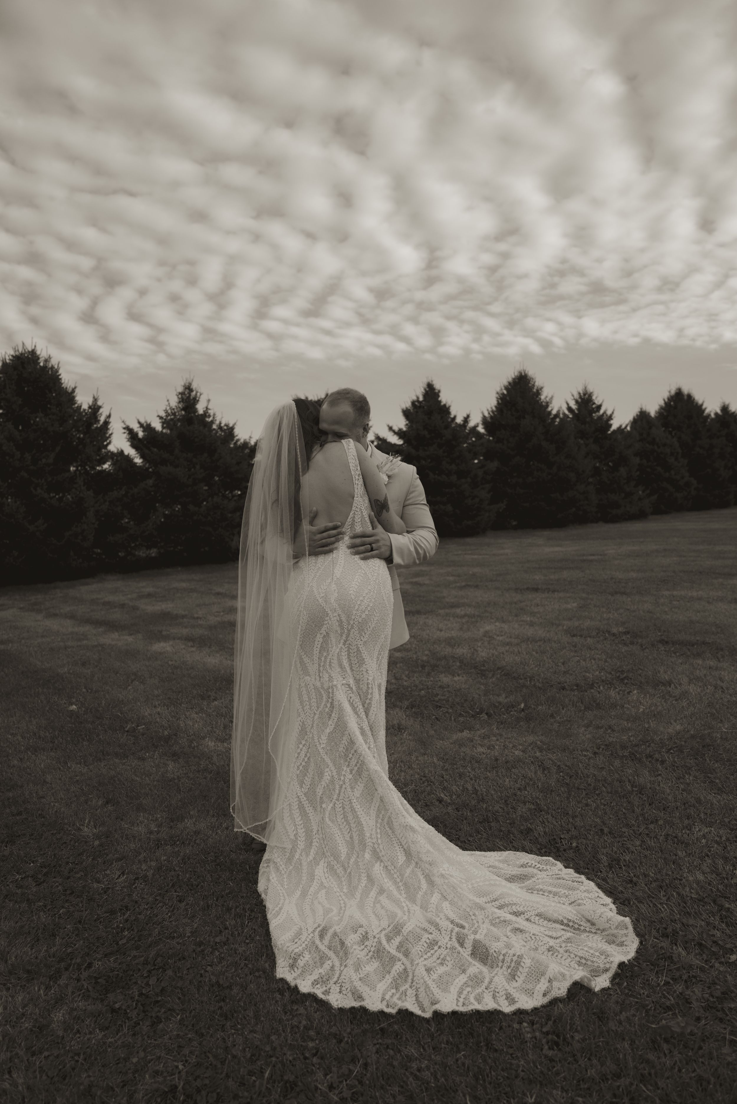 A flowing white wedding dress creates an ethereal silhouette against a cloudy sky.