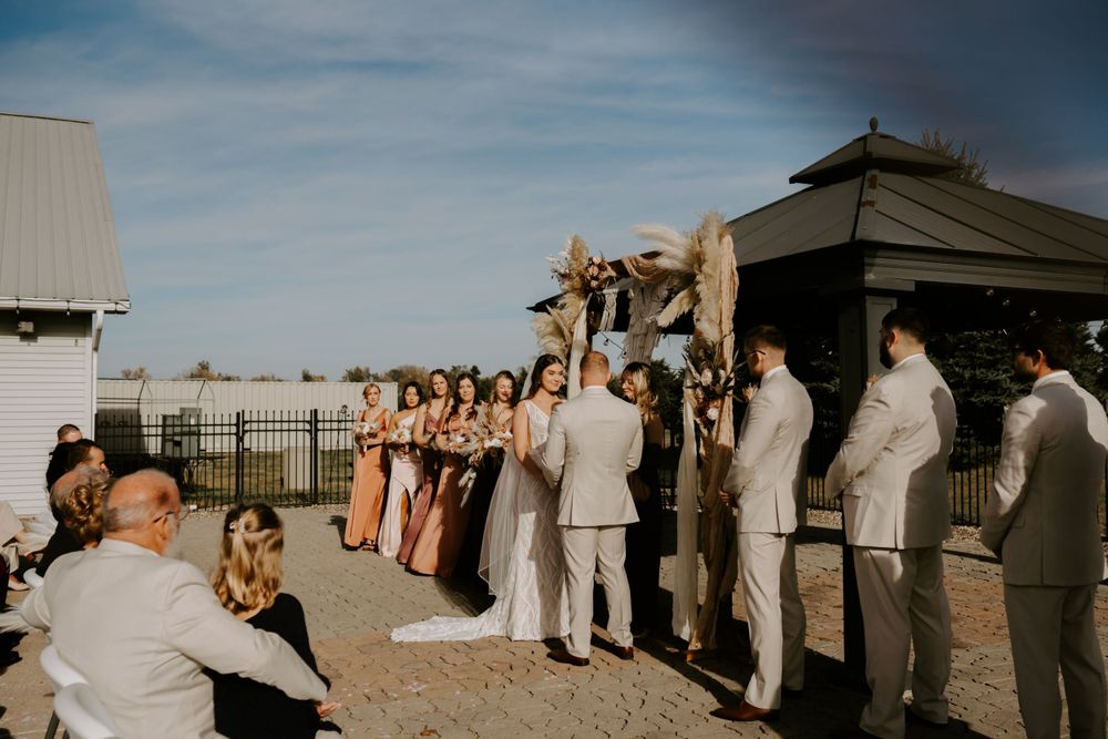 Wedding guests gather outdoors under blue skies for a celebration.