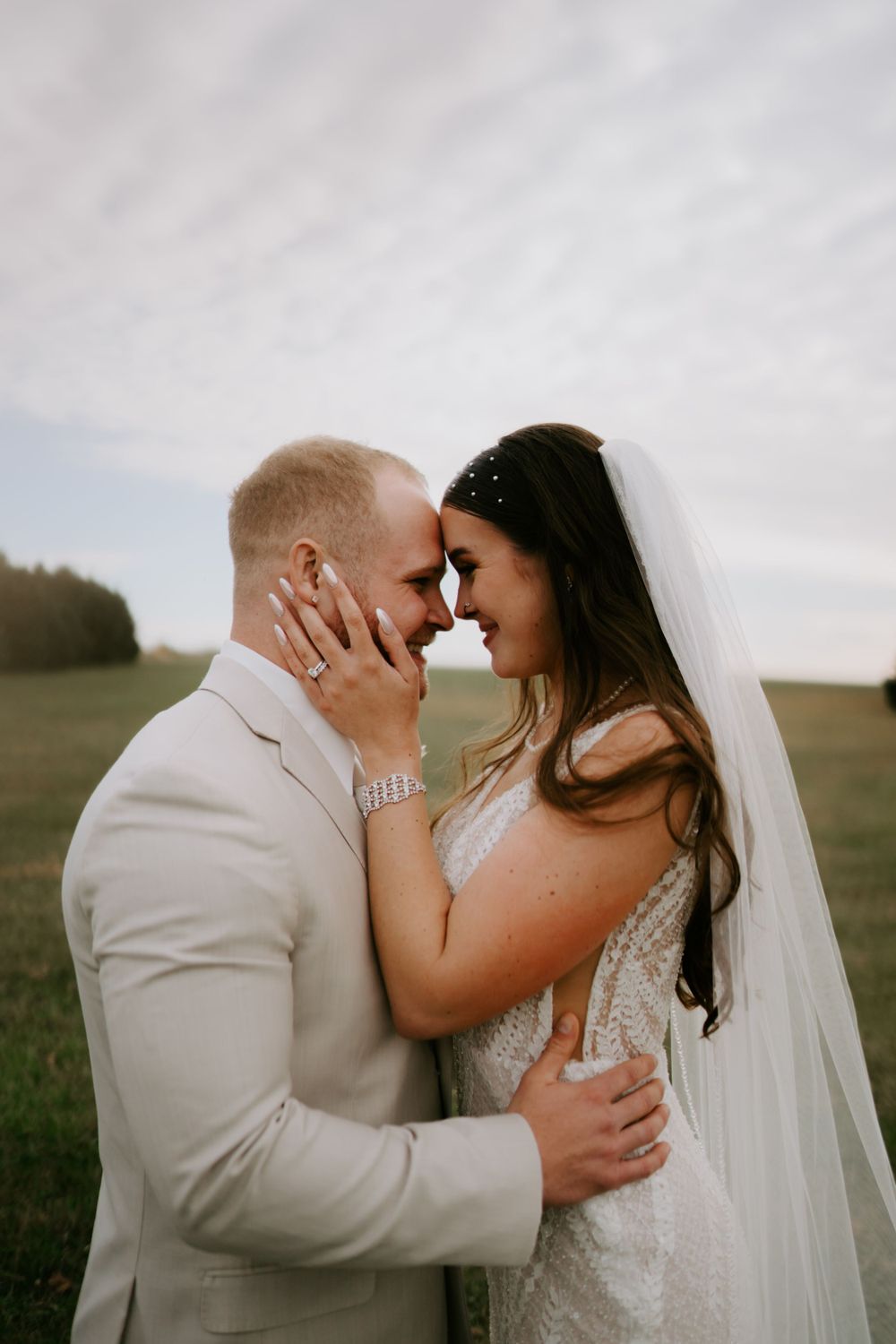 A tender moment shared between newlyweds in a sunlit field.