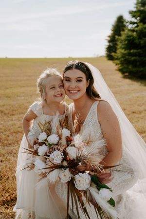Wedding party members share joyful moments while holding boho-style bouquets with pampas grass and roses.