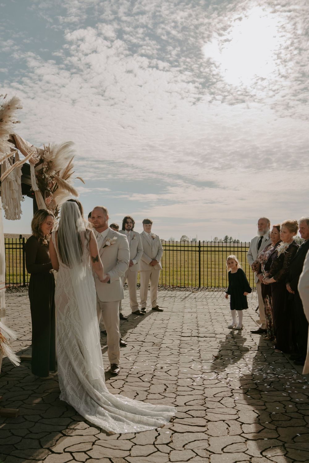 Wedding ceremony on a stone patio with guests watching the celebration unfold.