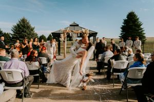 Outdoor wedding reception setup with white chairs and tables under blue skies.