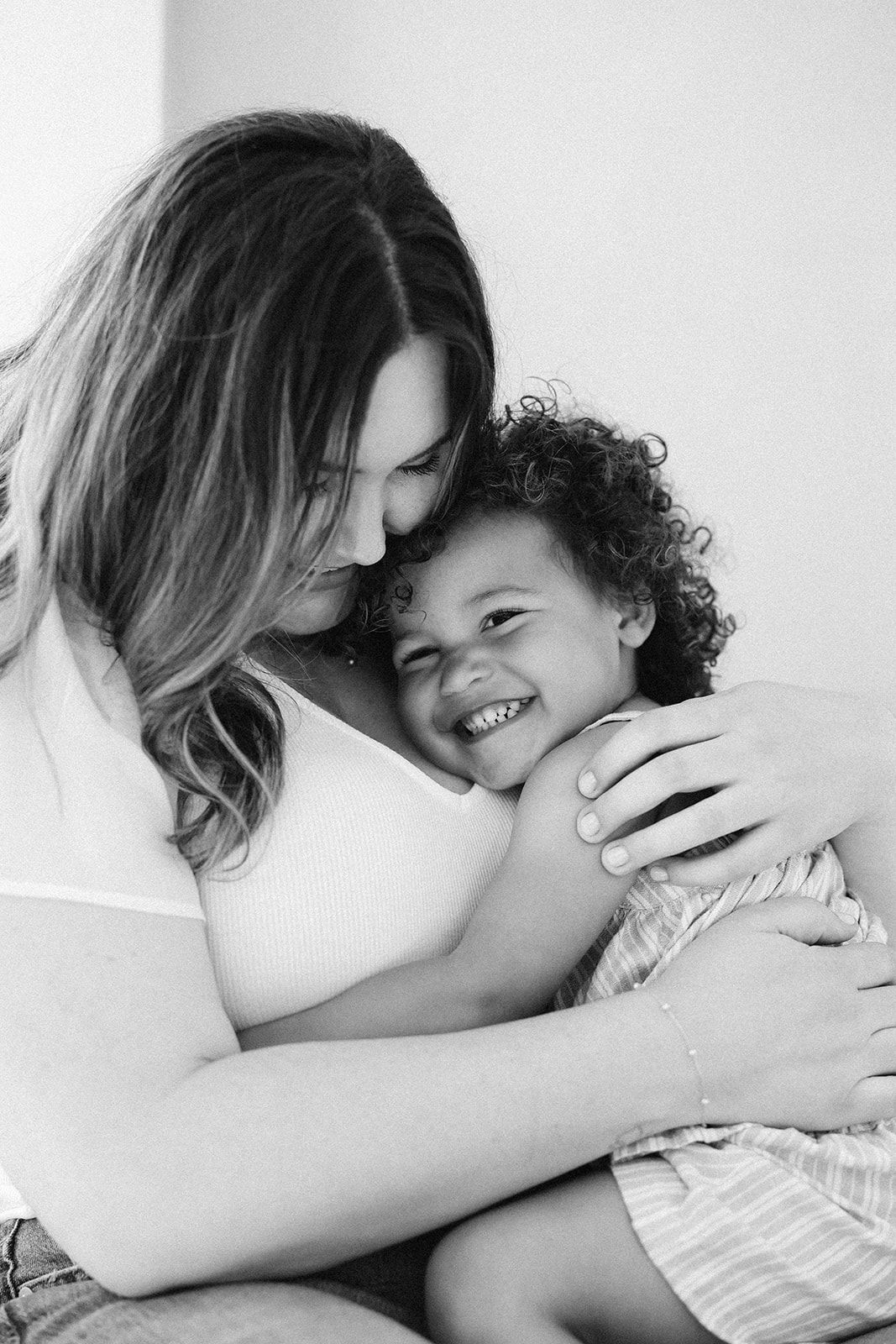 A tender black and white portrait of a parent and child sharing a joyful embrace and loving moment together.