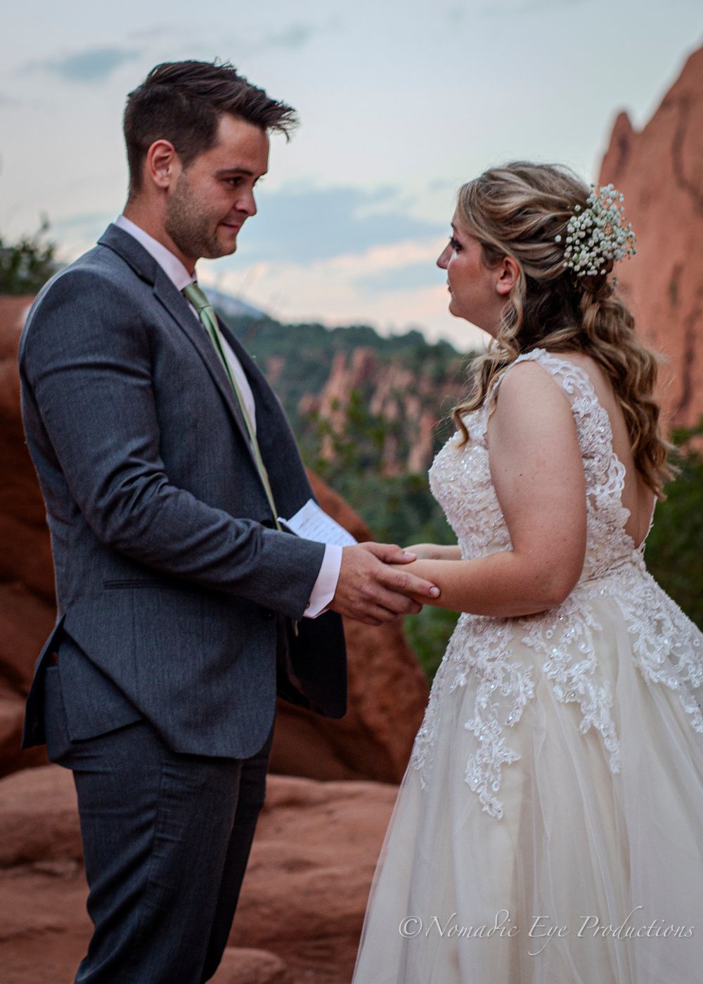 A couple shares a romantic moment during their wedding ceremony against scenic red rock formations.